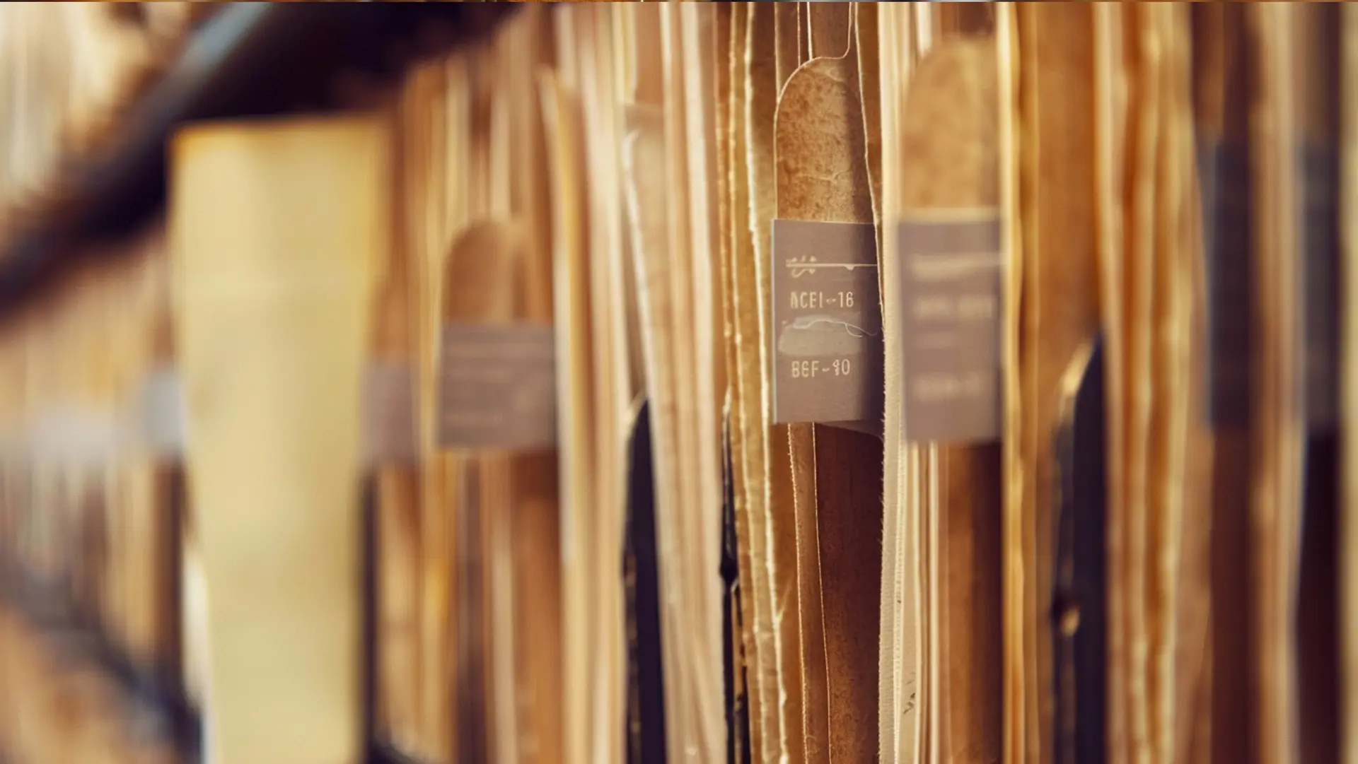 Alte Aktenordner mit grauen Rückenetiketten dicht gereiht in Bibliotheksarchiv