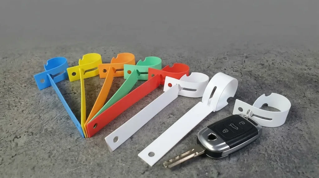 Bunte Kunststoff-Schlaufenetiketten in verschiedenen Farben neben Autoschlüssel – Schlaufenetiketten