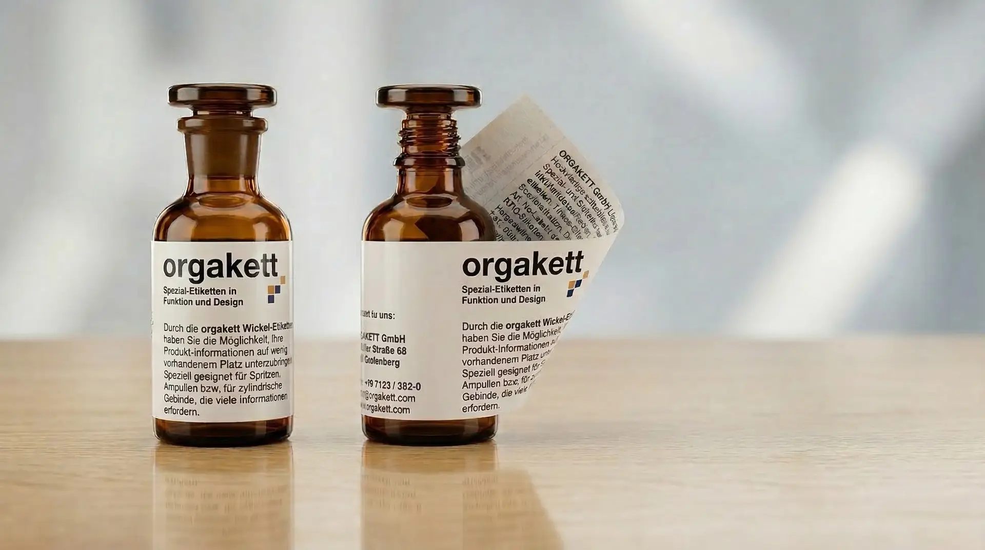 Zwei Braunglas-Fläschchen mit Wickeletikett auf Holztisch – Etiketten für Spritzen und Ampullen